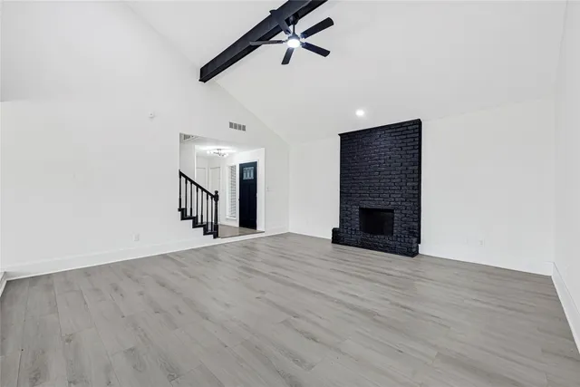 an empty room with wooden floor fireplace and windows