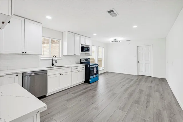 a kitchen with stainless steel appliances a refrigerator sink and white cabinets