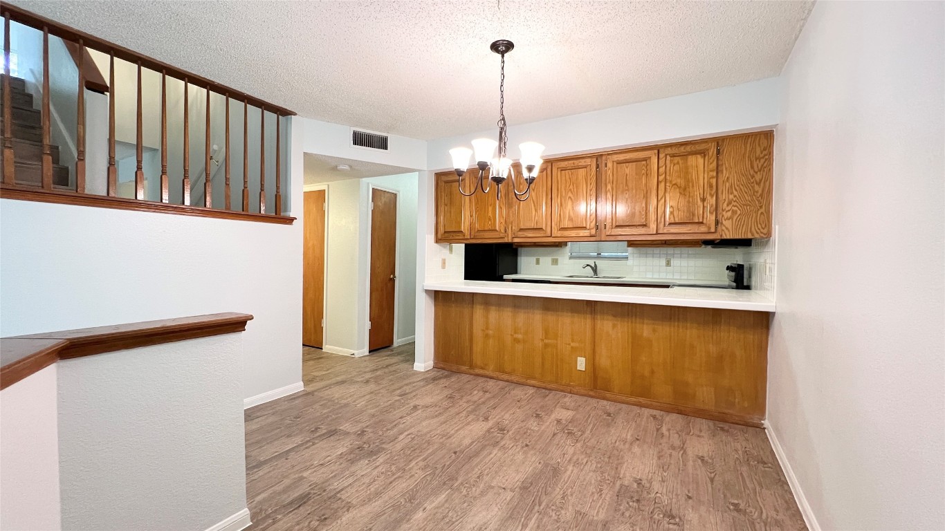 9201 Simmons Road, Unit 101 Austin, TX 78759 - Photo 2 of 10 a kitchen with stainless steel appliances granite countertop a refrigerator a stove and a sink with wooden floor