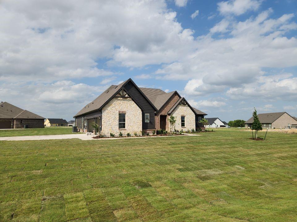 2305 Gypsum Street Krum, TX 76249 - Photo 3 of 22 Exterior featuring stone and dark siding with gabled roofs, a covered entry, and a two-car garage