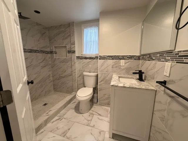 a bathroom with a granite countertop sink a toilet and shower