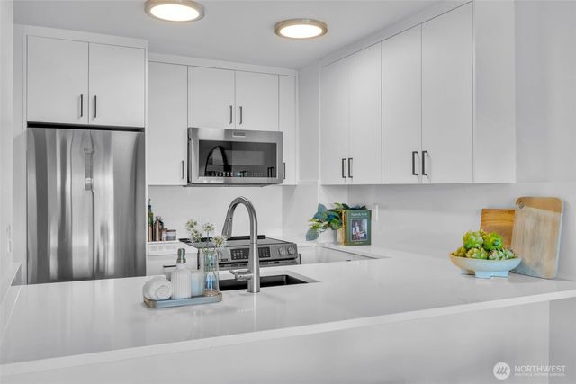 a kitchen with stainless steel appliances a sink a refrigerator a microwave a sink and cabinets