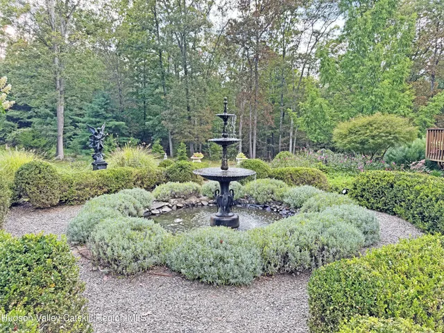 a backyard of a house with lots of green space and fountain