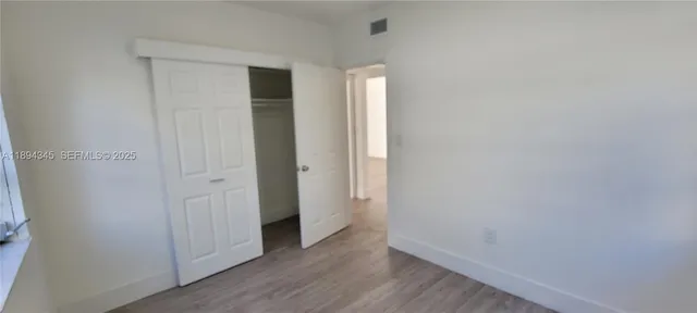 an empty room with wooden floor and closet