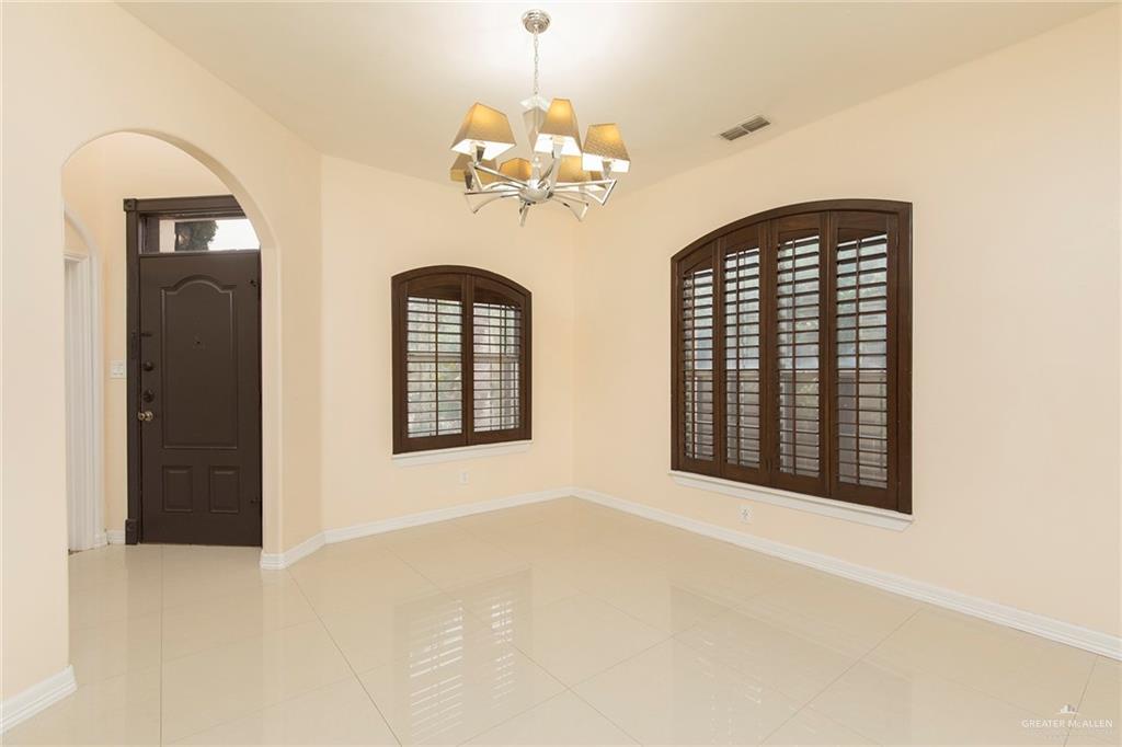 2001 Quail Lane Mission, TX 78572 - Photo 3 of 28 Spacious room featuring light tile flooring, arched entryways, and two arched windows with dark wood plantation shutters