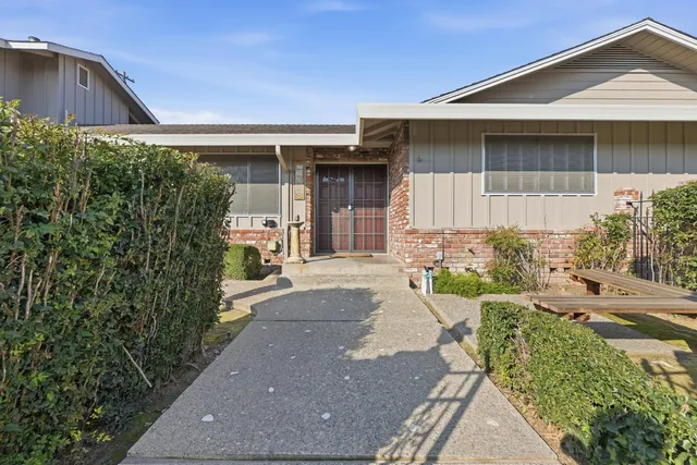 a front view of a house with a yard and potted plants