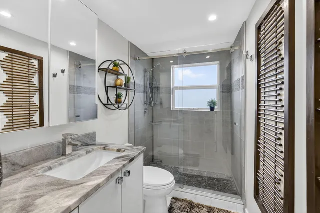 a bathroom with a granite countertop toilet a sink and a mirror