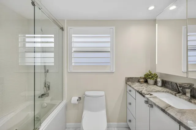 a bathroom with a granite countertop sink toilet and shower