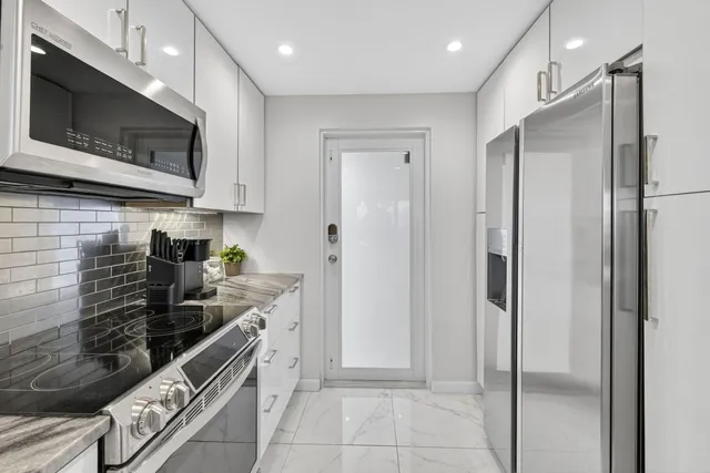 a kitchen with stainless steel appliances granite countertop a refrigerator and a stove top oven