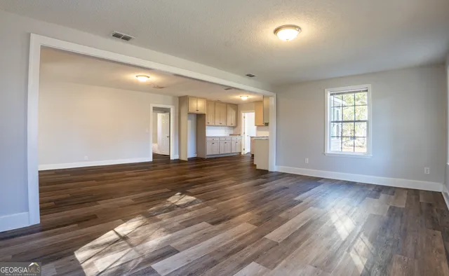 an empty room with wooden floor and windows