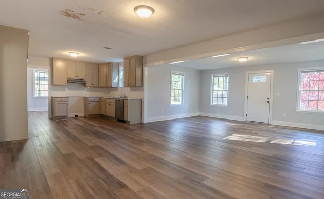 an empty room with wooden floor and windows