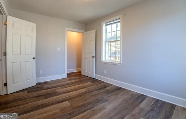 an empty room with wooden floor and windows
