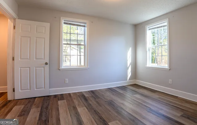 an empty room with wooden floor and windows