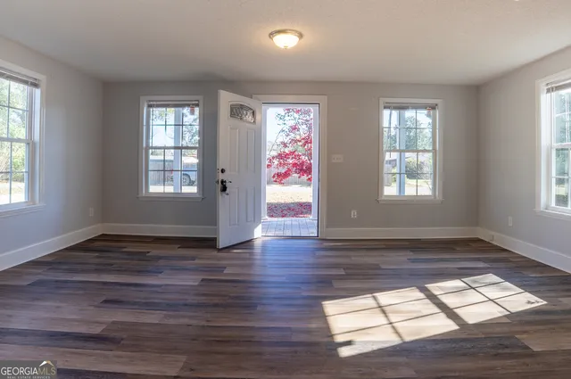 a view of an empty room with wooden floor and a window
