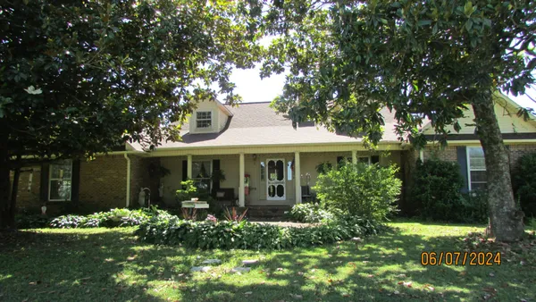 a view of a house with brick walls and a yard with plants