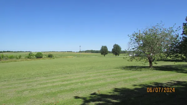 a view of green field with trees in the background