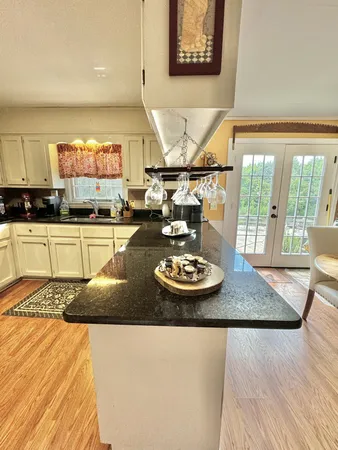 a kitchen with a stove a sink and a dining table with wooden floor
