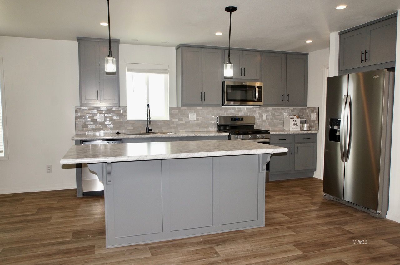 a kitchen with stainless steel appliances granite countertop a sink a stove a refrigerator and island with wooden floor