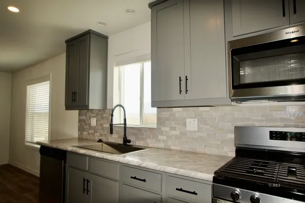 a kitchen with stainless steel appliances granite countertop a sink stove and microwave