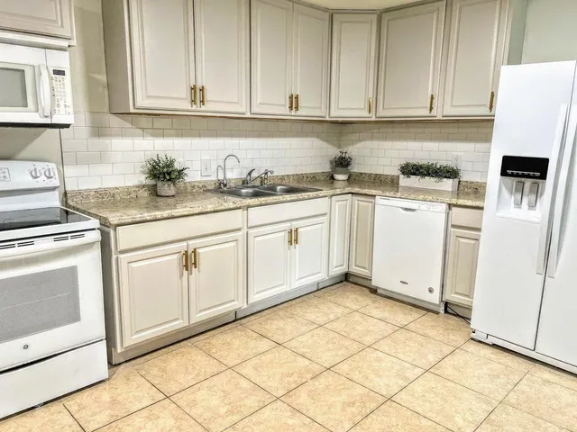 a kitchen with granite countertop white cabinets and white appliances