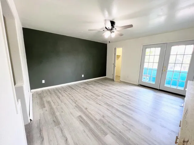 a view of an empty room with a window and wooden floor