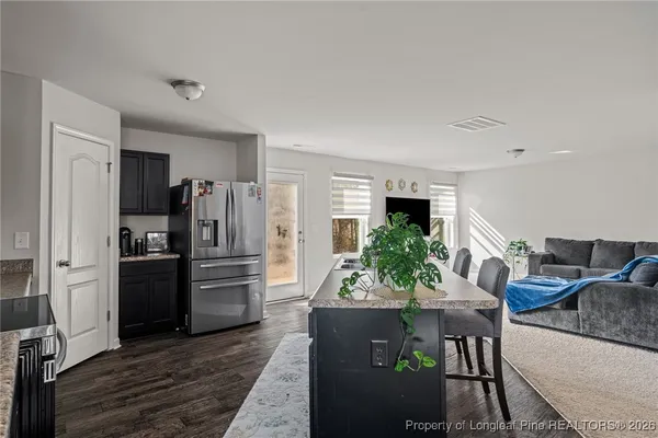 a kitchen with stainless steel appliances kitchen island granite countertop a refrigerator and a stove top oven