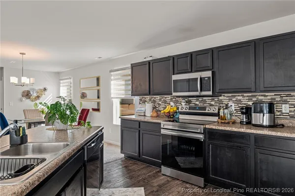 a kitchen with stainless steel appliances granite countertop a sink dishwasher stove and microwave with wooden cabinets
