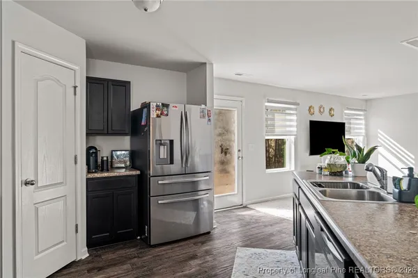 a kitchen with granite countertop a refrigerator stove and sink