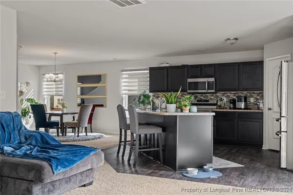 a kitchen with a dining table chairs and refrigerator
