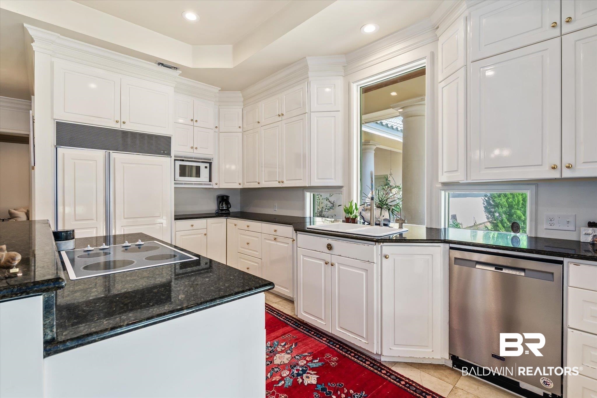 6341 Raintree Road Fairhope, AL 36532 - Photo 8 of 40 Kitchen with dark stone counters, built in appliances, white cabinets, sink, and light tile patterned flooring
