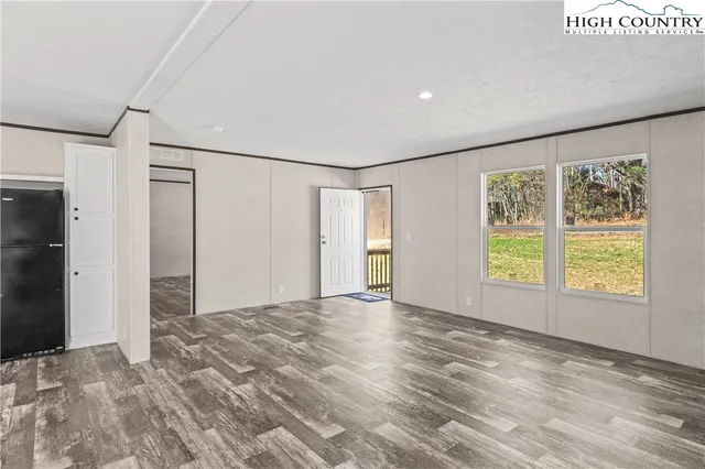 a view of an empty room with a window and wooden floor