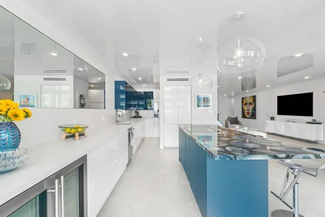 a view of a kitchen with kitchen island stainless steel appliances a sink stove and cabinets