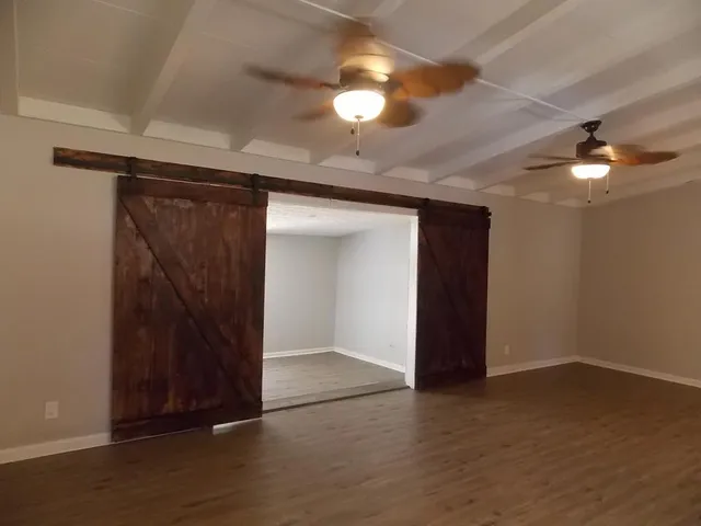 an empty room with wooden floor and fan