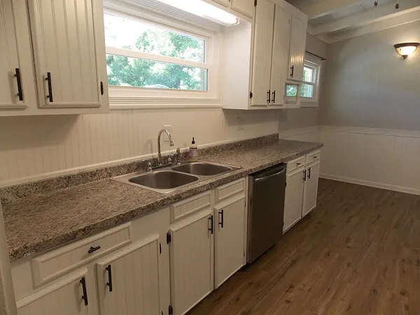 a kitchen with stainless steel appliances granite countertop a sink a stove and cabinets with wooden floor