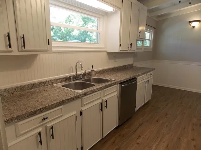 a kitchen with stainless steel appliances granite countertop a sink a stove and cabinets with wooden floor