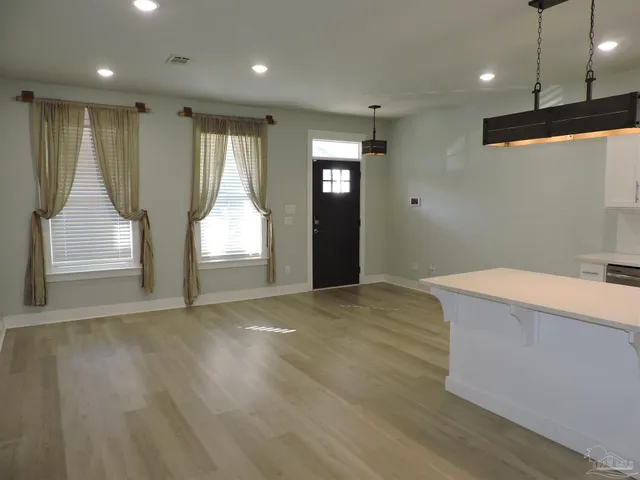 a view of an empty room with wooden floor and windows