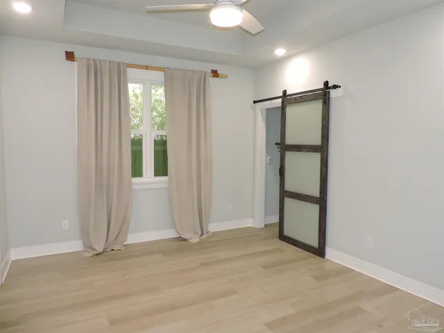 a view of empty room with wooden floor and fan