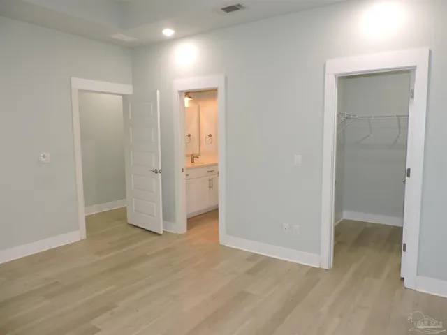 an empty room with wooden floor & closet area