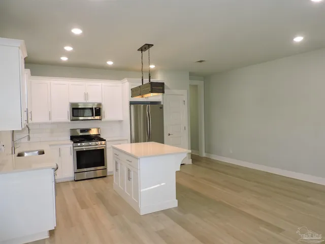 a kitchen with kitchen island stainless steel appliances a stove refrigerator sink and microwave