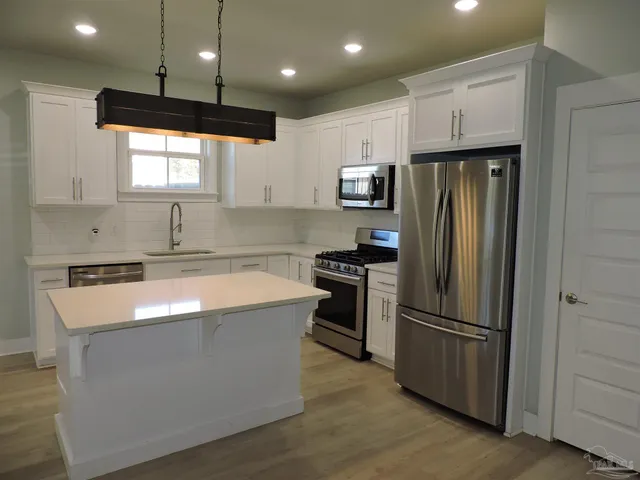 a kitchen with stainless steel appliances granite countertop a refrigerator a sink and a stove