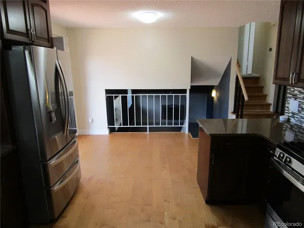 a view of kitchen with stainless steel appliances granite countertop a refrigerator and a stove