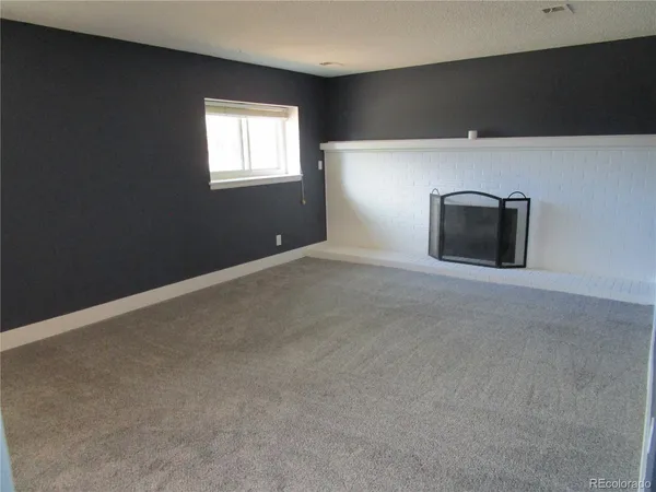 a view of an empty room with a fireplace and a window