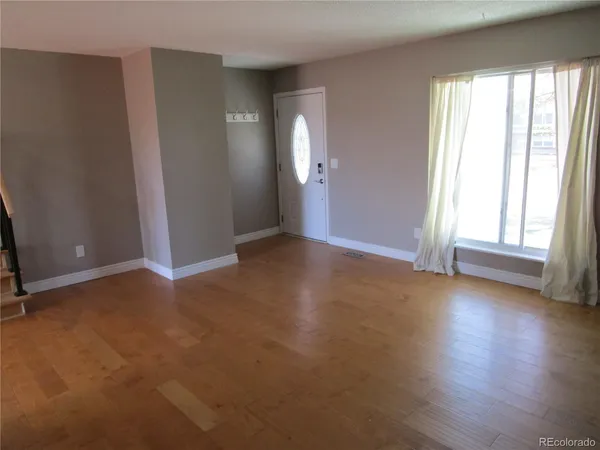 an empty room with wooden floor and windows