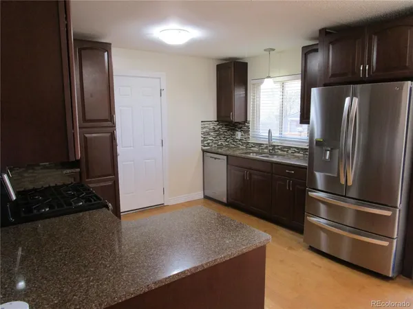 a kitchen with stainless steel appliances granite countertop a refrigerator and a stove
