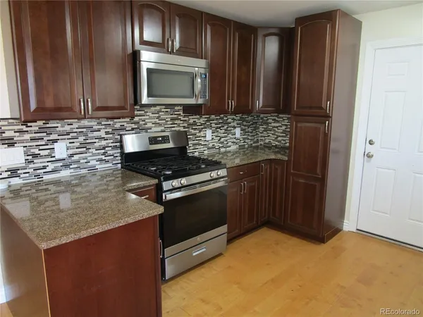 a kitchen with stainless steel appliances granite countertop a stove a sink and a microwave