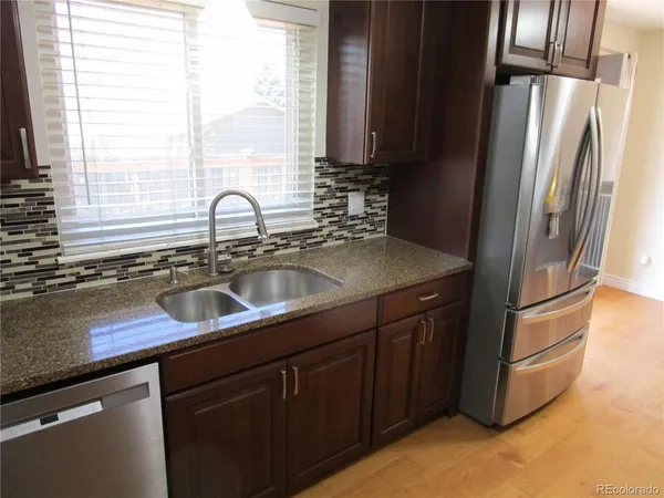 a kitchen with stainless steel appliances granite countertop a sink refrigerator and window