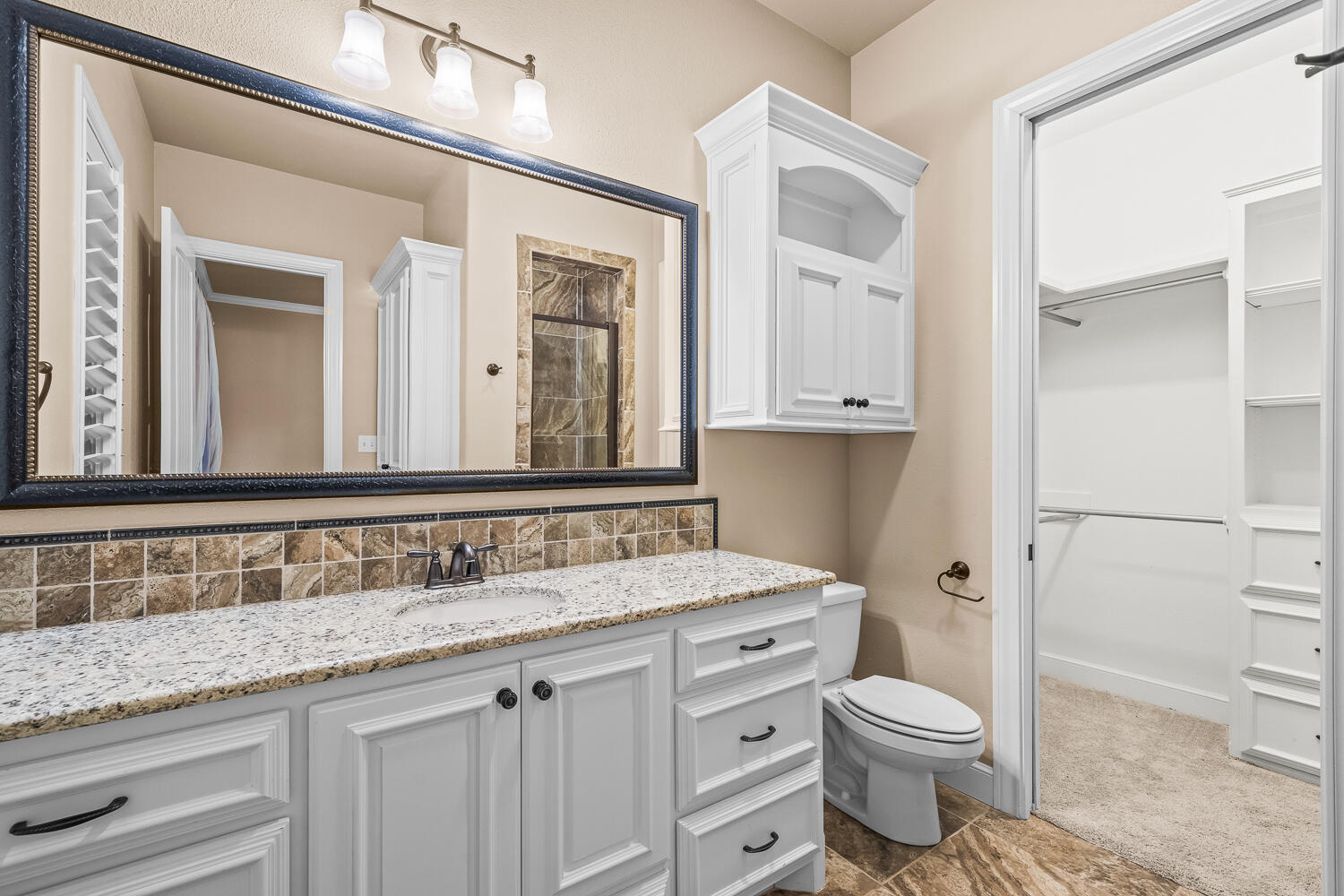 4509 103rd Street Lubbock, TX 79424 - Photo 67 of 94 a bathroom with a granite countertop toilet sink and mirror