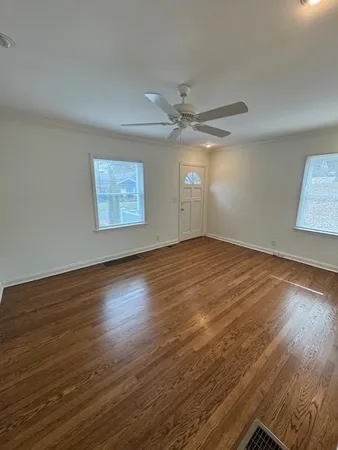 a view of an empty room with wooden floor and a window