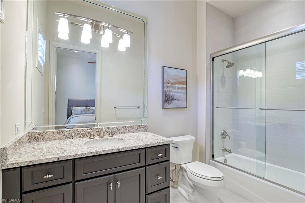 16459 Seneca Way Naples, FL 34110 - Photo 27 of 50 a bathroom with a granite countertop sink a toilet and shower