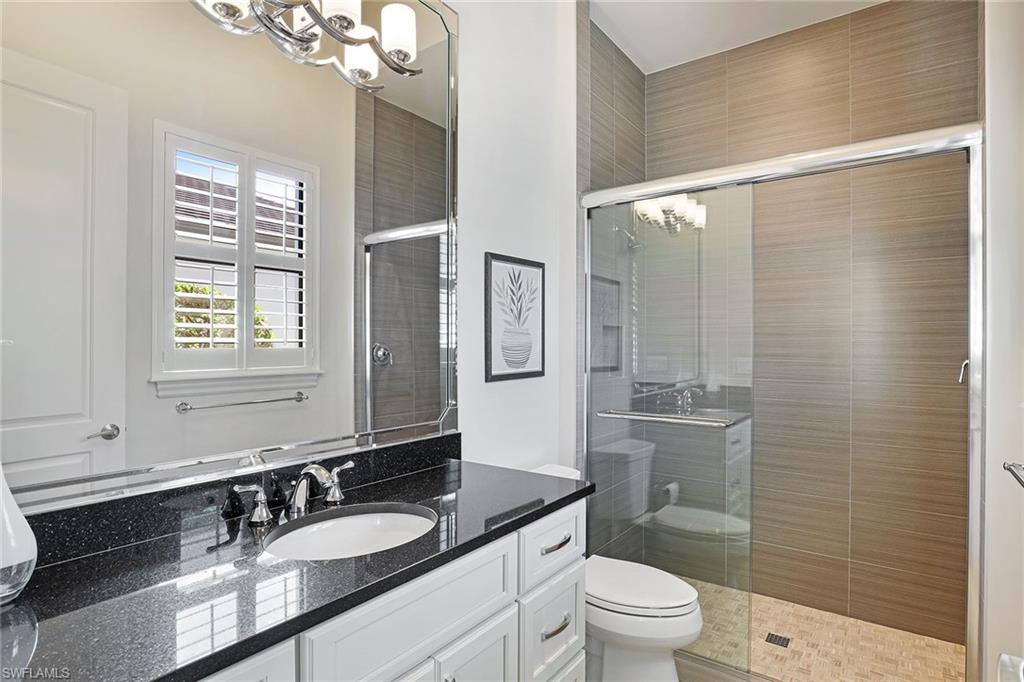 16459 Seneca Way Naples, FL 34110 - Photo 29 of 50 a bathroom with a granite countertop sink a toilet a mirror a vanity and shower